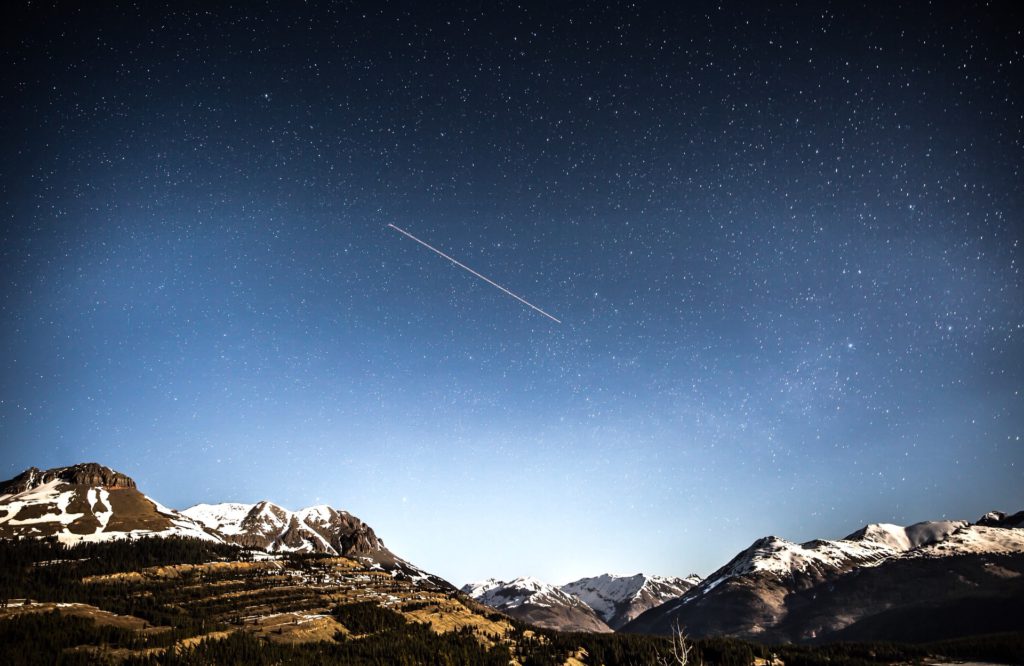 shooting star over snow covered mountains