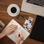 Person holding ballpoint pen writing on notebook