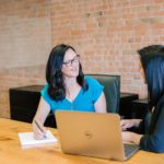 Woman in t-shirt sitting beside woman in suit jacket